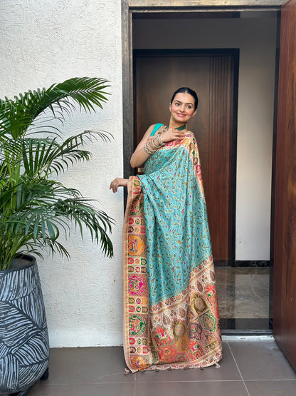 Woman in a colorful saree standing in a doorway with a plant to her left. Indraneel Meenakari Jacquard Floral Saree for Women | Yuvani Vesture