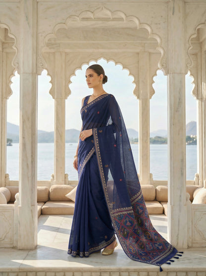 Woman in a blue saree standing in front of an archway with a scenic view. Navy Blue Patola Jamdani Cotton Saree for women
