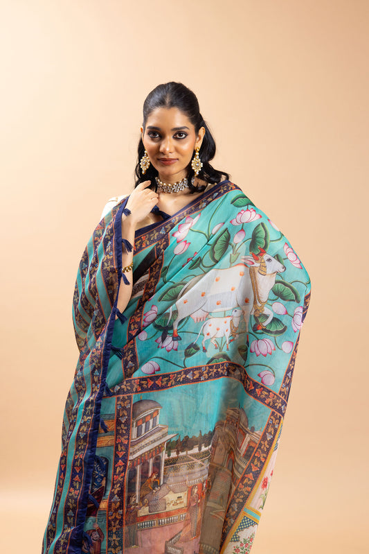 Woman wearing a colorful saree with a scenic design on a beige background Shringar Pichwai Chanderi Saree | Pichwai Saree | yuvani vesture