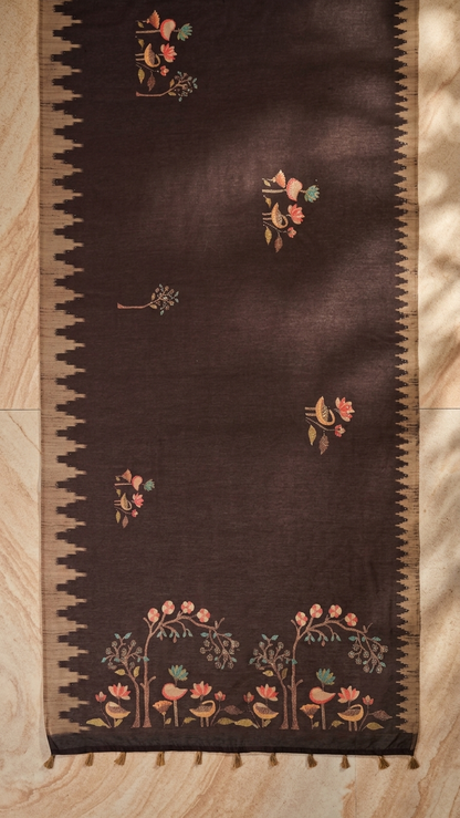 Brown Bird & Tree Handwork Saree | Yuvani Vesture Decorative brown rug with floral patterns on a wooden floor